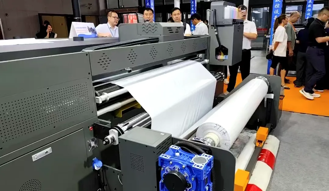 Baoswei heavy-duty roll printer processing white flexible substrate with 1-ton jumbo roll system — visitors observing stable continuous production