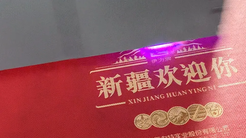 打印机喷头近距离作业特写,在红色无纺布表面精准输出图案与文字细节