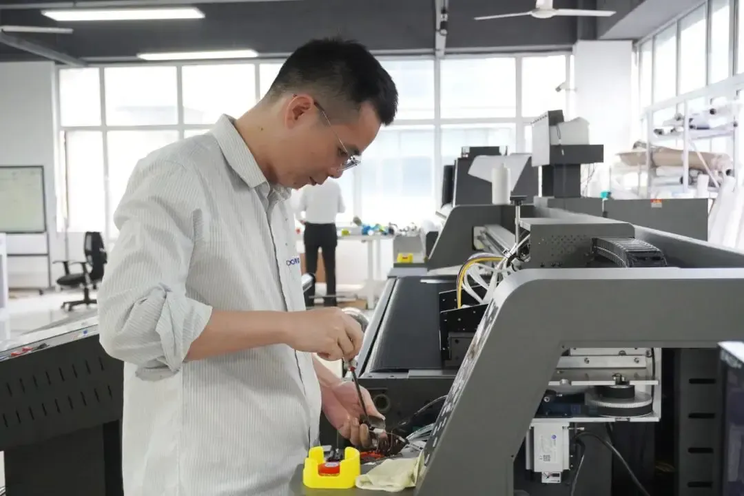 Baosiwei technician debugging printing equipment in a spacious workshop, using tools to operate internal components of the device